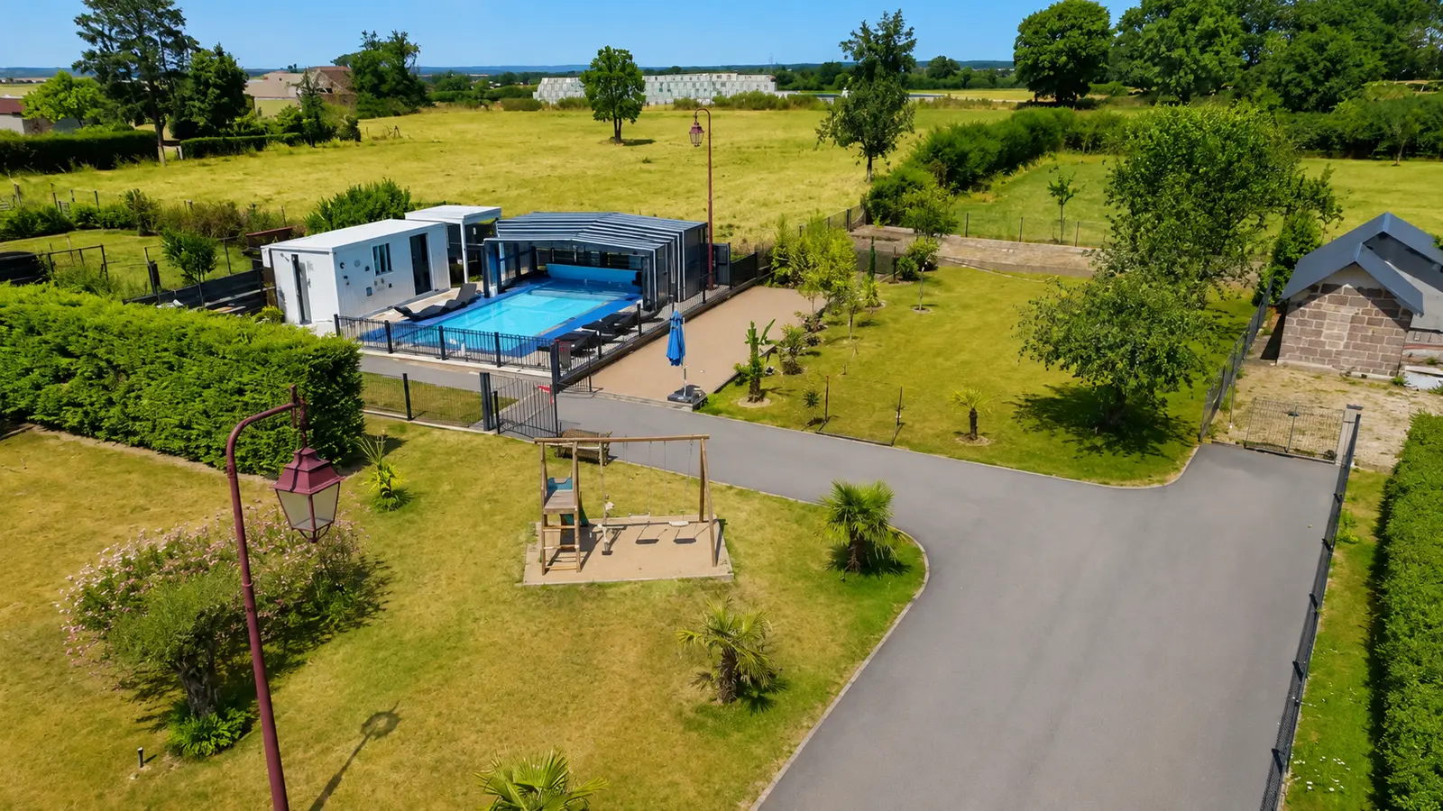 Vue aérienne du terrain du gîte Lau’Livier : la piscine couverte, le bungalow et l’aire de jeux