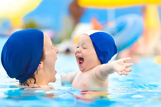 jeux d'eaux en famille maman et bébé dans la piscine